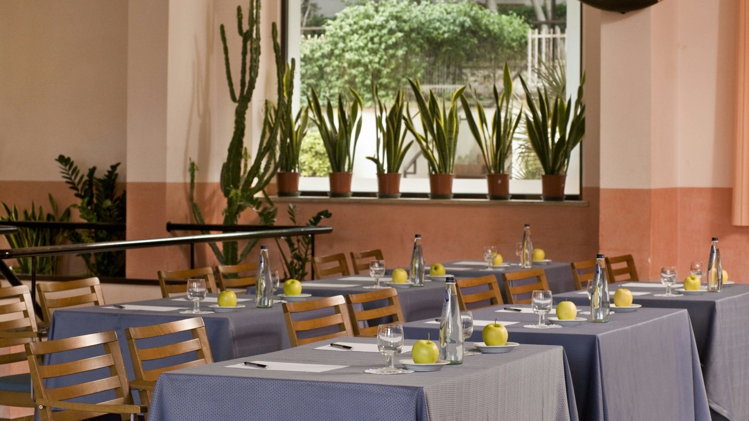 Un restaurante con mesas dispuestas para comer, con vistas a la vegetación a través del ventanal.