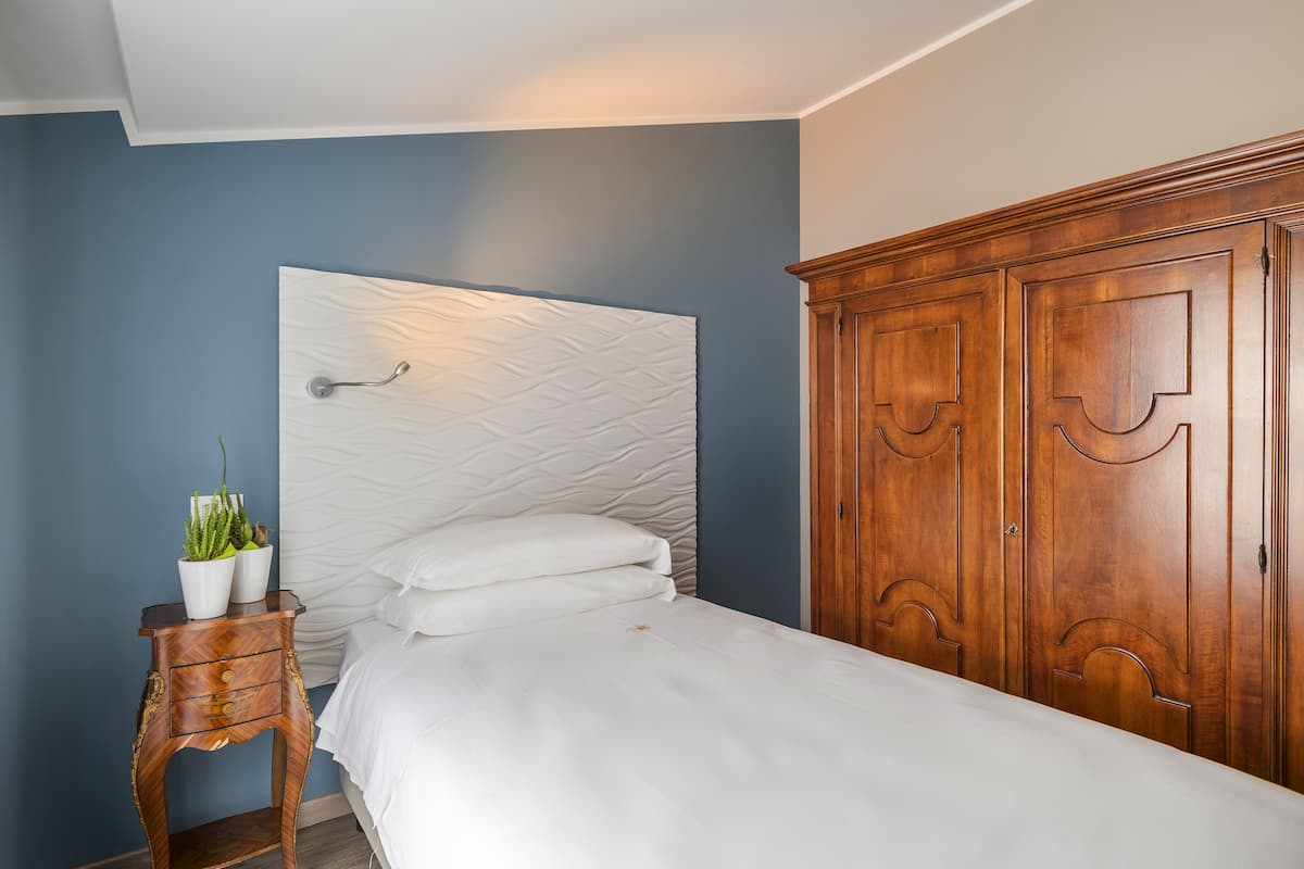 Ein Schlafzimmer mit einem Bett, einem Nachttisch mit Pflanze und einem Holzschrank.