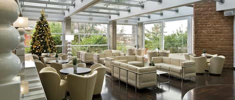 Ein moderner Lounge-Bereich mit Ledersofas, runden Tischen und einem Weihnachtsbaum.