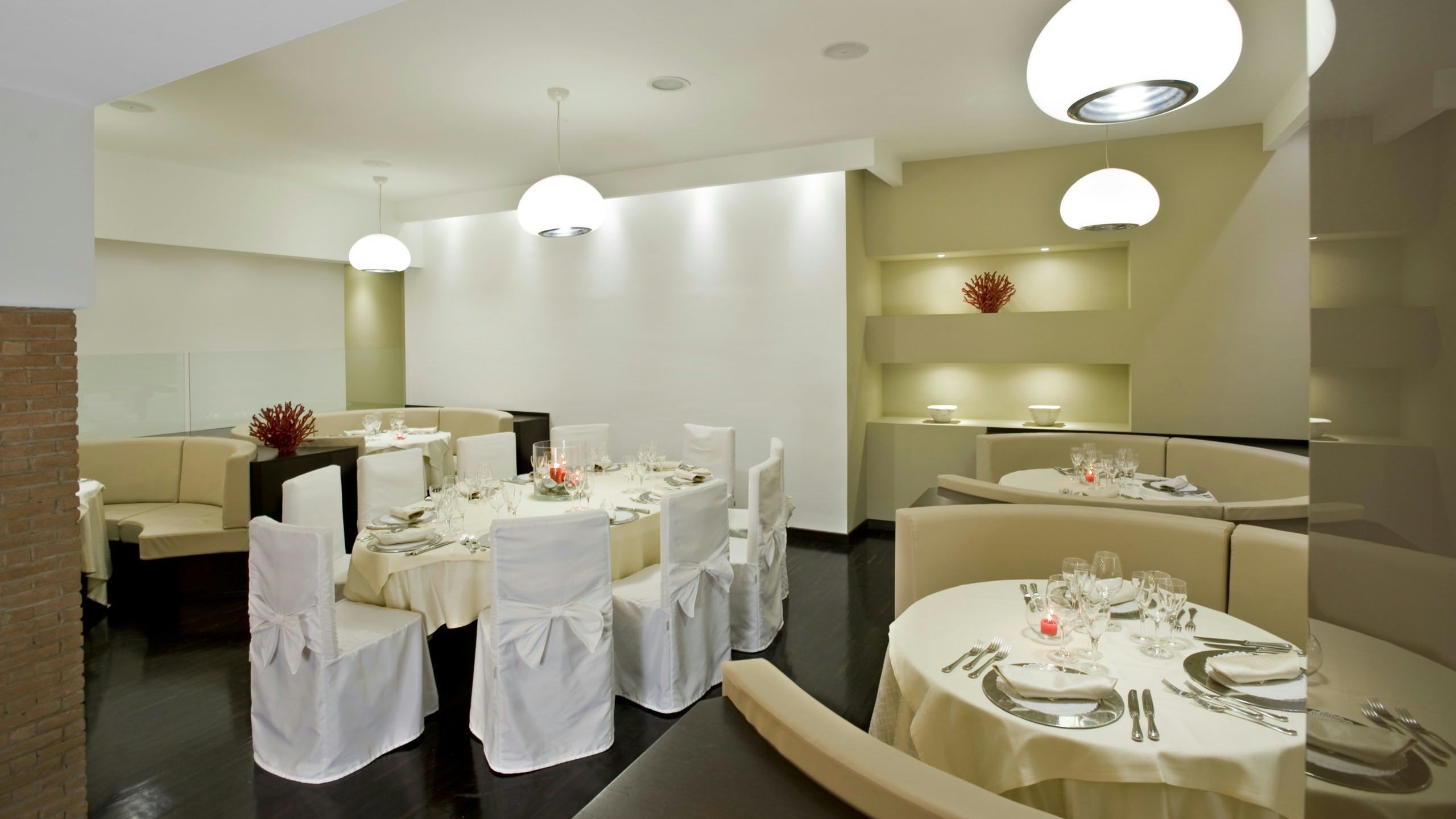 Un comedor moderno con mesas redondas, manteles blancos y sillas cubiertas de blanco.