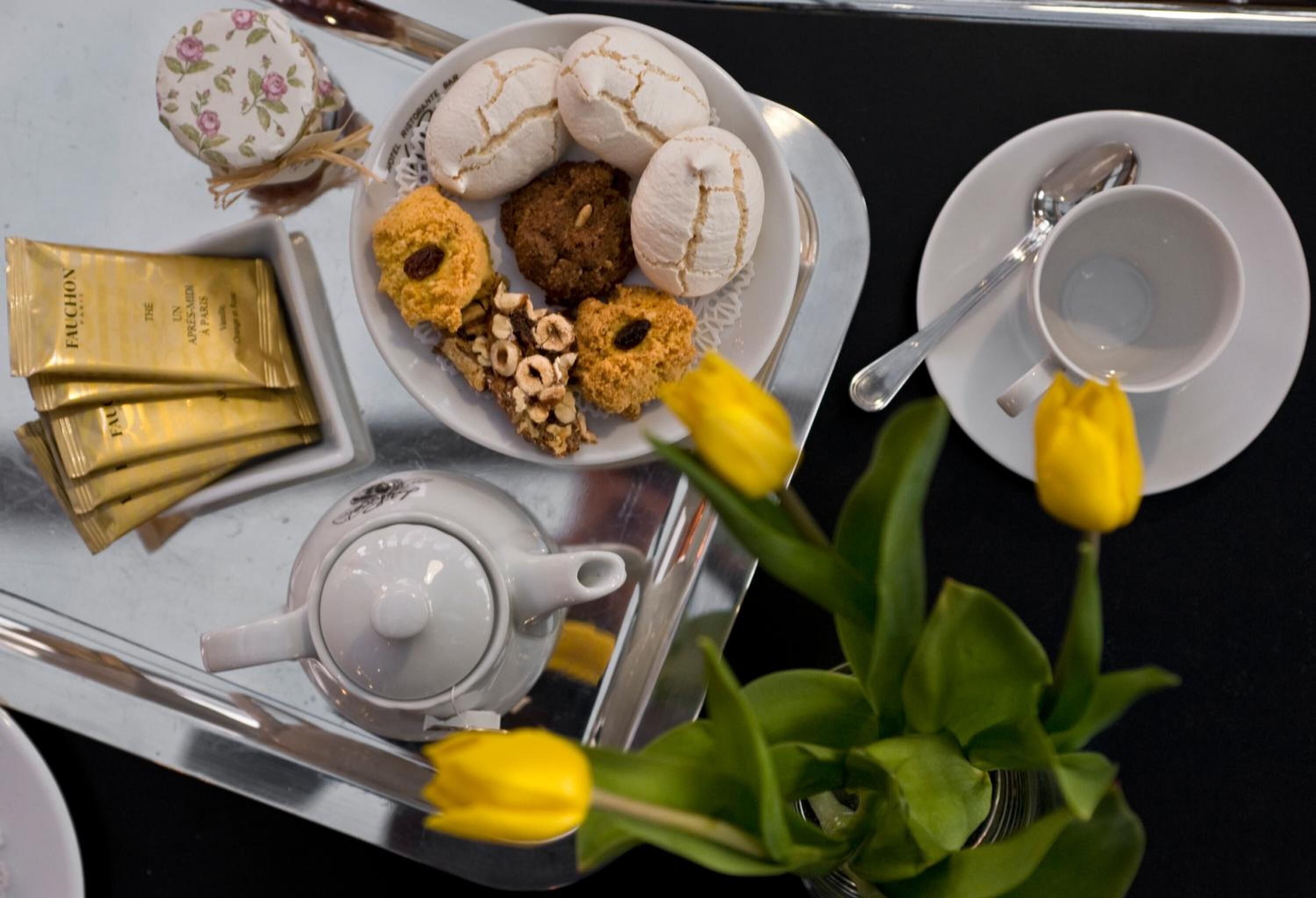 Una bandeja con galletas, una tetera y una taza sobre una mesa.