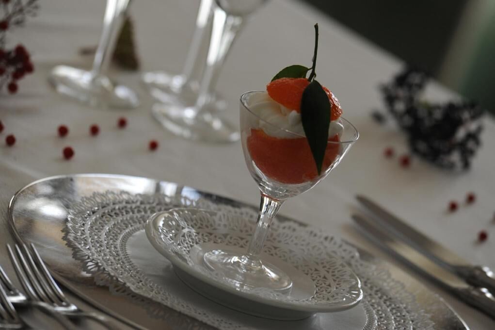 A dessert in a glass cup on a white plate with a lace doily underneath.