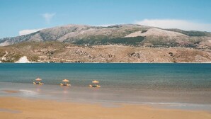 A beach with clear turquoise water, a sandy shore, and a mountainous backdrop. - Daphne's Boutique Apartments (Kefalonia)