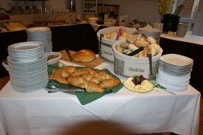 A buffet table with various food items and stacked plates.