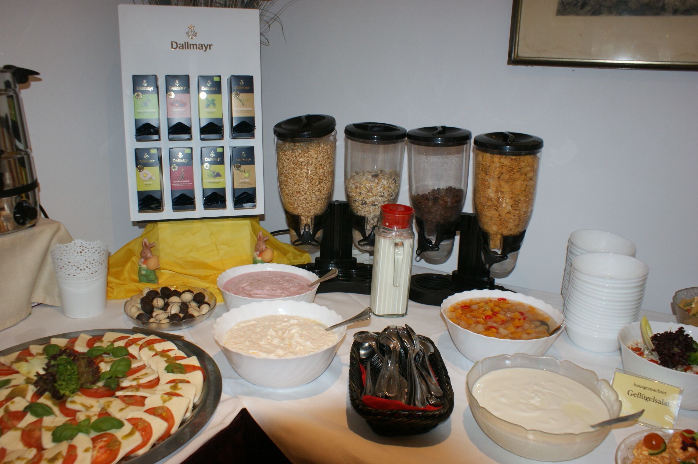 A buffet table with various food items, including a pizza, bowls of soup, and containers of cereal.