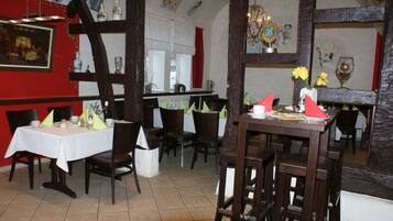 Een restaurant met houten meubels, witte tafelkleden en rode muren.