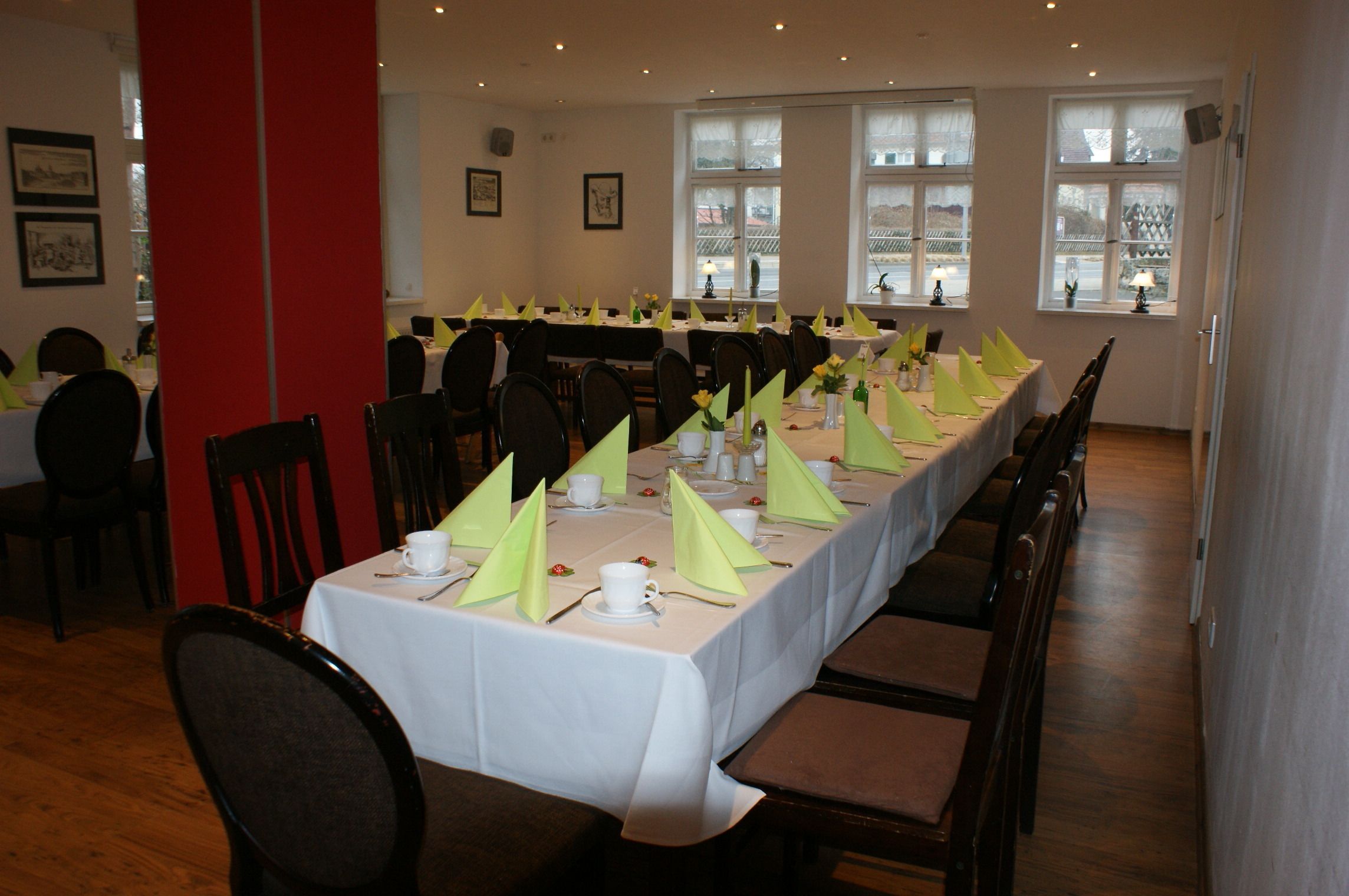 A dining area with tables set for a meal, chairs, and a red pillar.