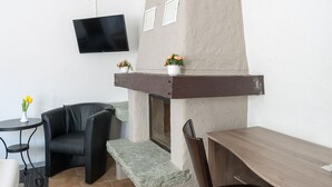 Un soggiorno moderno con camino, una TV a schermo piatto montata a parete e un’accogliente area salotto con divano e poltrone.