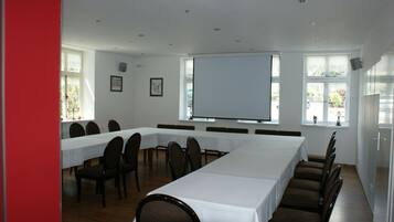 Una sala conferenze con lunghe tavolate e sedie, ampie finestre e uno schermo di proiezione.