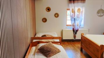 A room with a bed, a wooden chair, a small table, and a radiator.