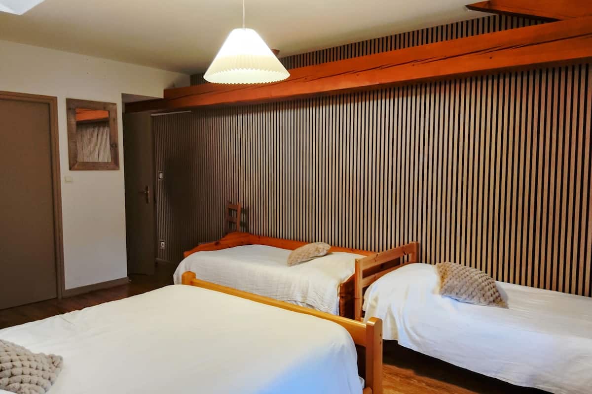 A room with two wooden beds, a slatted wooden wall, and a hanging light fixture.