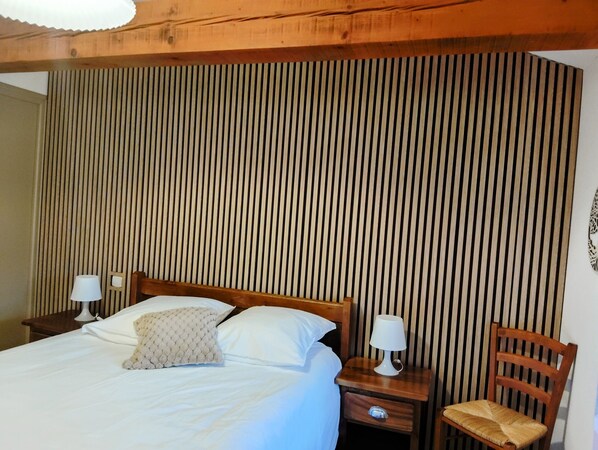 A bedroom with a bed, two bedside tables, a chair, and a wooden slat wall.