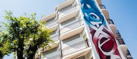 A multi-story building with balconies and a large mural on the side.