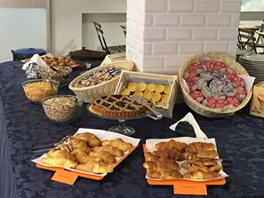 A buffet table with various food items including pastries, sandwiches, and containers of yogurt. - Hotel X (Ravenna)