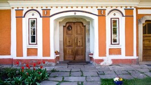 A building with a wooden double door, two windows with white frames, and a decorative archway above the door. - Růžová chalupa u Šimánků (Rtyne v Podkrkonosí)