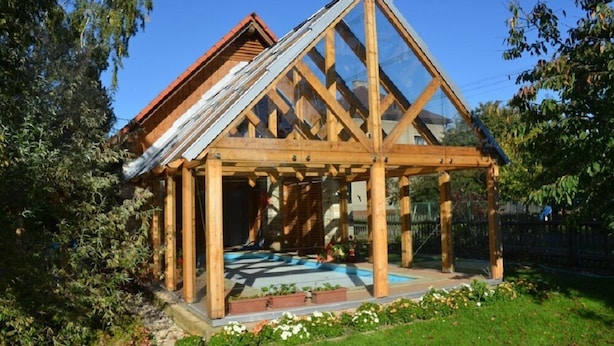 A wooden structure with a triangular roof and glass panels, surrounded by greenery. - Růžová chalupa u Šimánků (Rtyne v Podkrkonosí)
