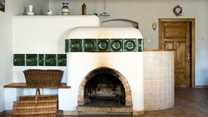 A rustic kitchen with a brick oven, white tiled walls, and a wooden door. - Růžová chalupa u Šimánků (Rtyne v Podkrkonosí)