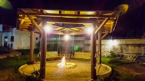 Un belvédère en bois avec un foyer au centre, entouré d’un espace de sièges circulaire.