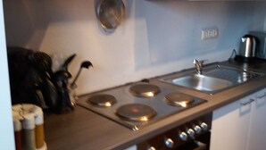 Una cocina con armarios blancos, estufa y pileta.