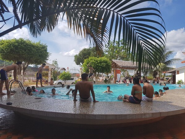 Una piscina al aire libre, sombrillas, sillones reclinables de piscina