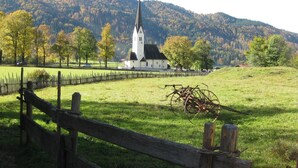 A rural landscape with a church, a wooden fence, and a field. - Gästehaus Gritscher (Schliersee)