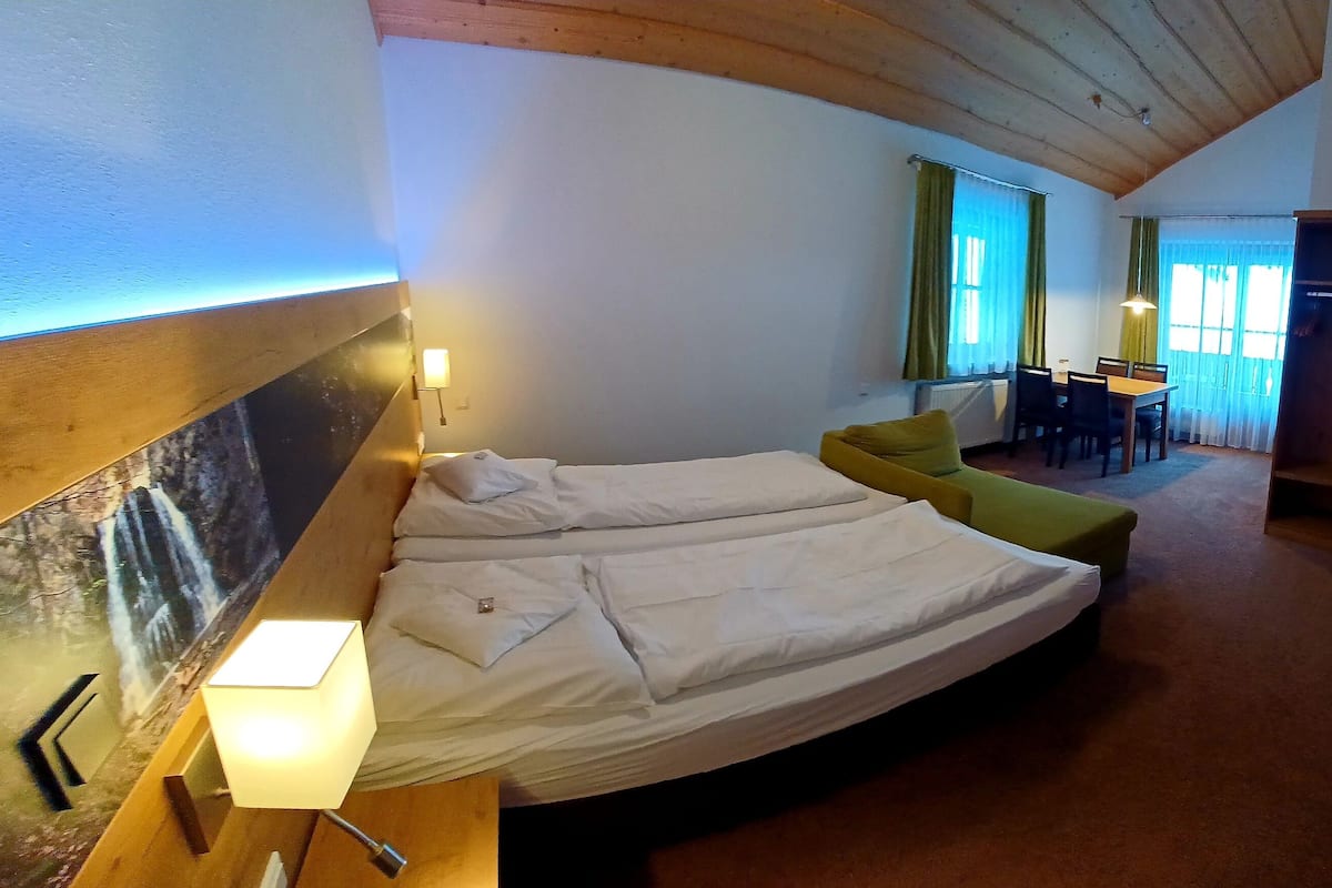 Une chambre avec deux lits, un coin repas et un téléviseur.