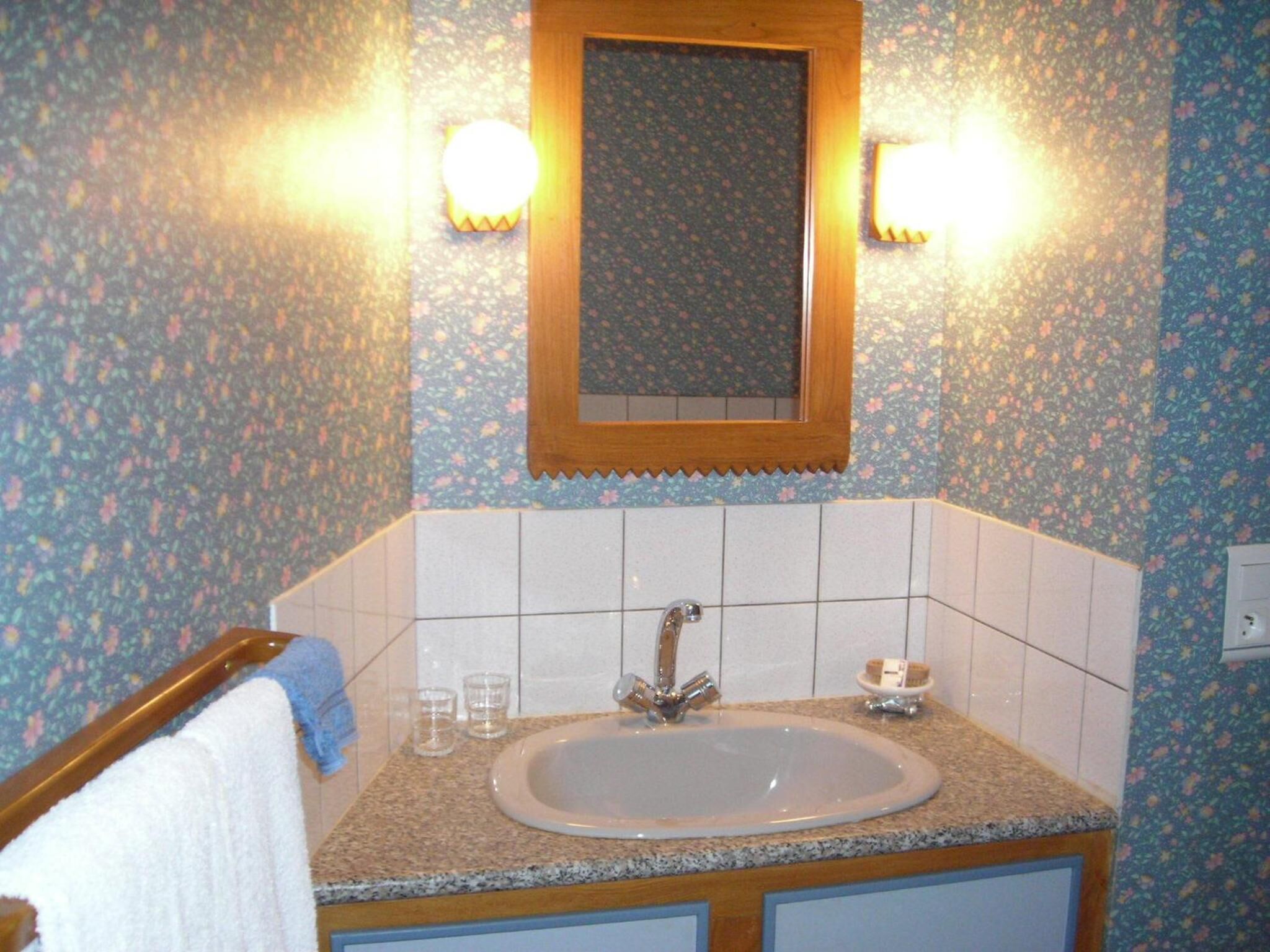 Un baño con lavamanos, espejo y dos luces en la pared.