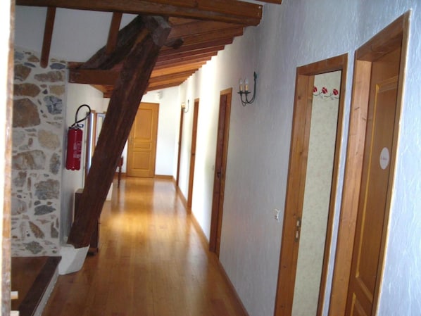 Un pasillo con pisos de madera, paredes de piedra y puertas de madera.
