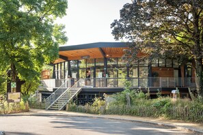 A modern building with a covered entrance, a staircase, and a fenced area with trees.