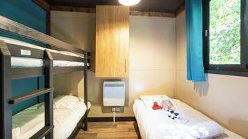 A bunk bed room with a window, a heater, and a small table with a teddy bear.