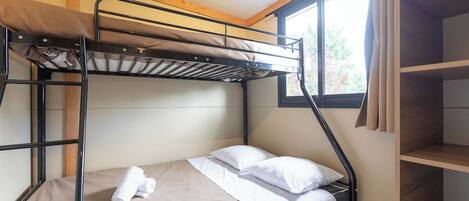 A bunk bed room with a window, a wooden ceiling, and a shelf unit.