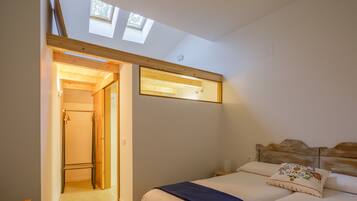 A bedroom with two beds, a skylight, and a wooden headboard.