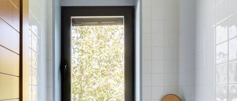 Un baño con ventana, un lavamanos, un espejo y dos toallas.