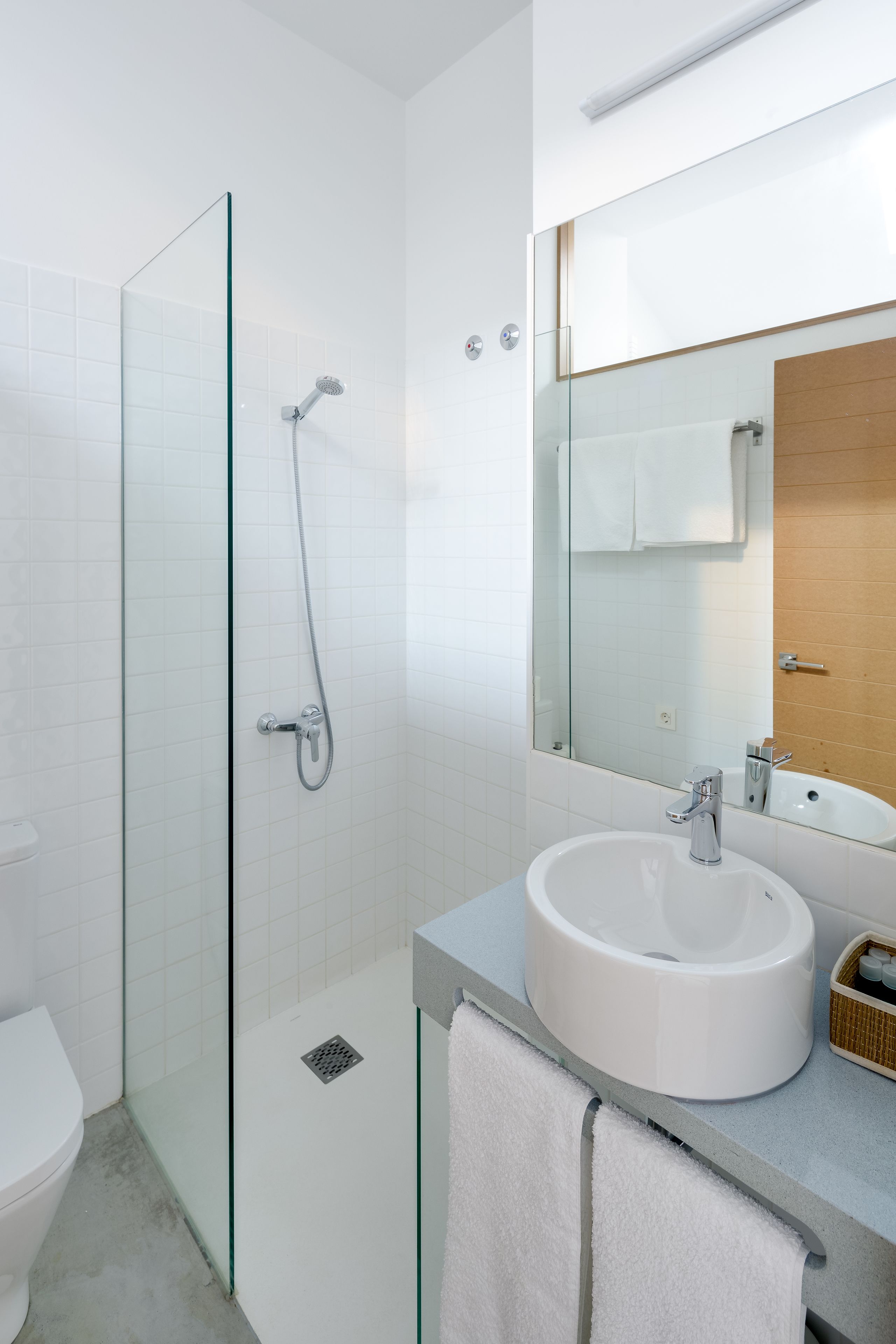 Un baño moderno con cabina de ducha de vidrio, un lavabo blanco y un espejo grande.