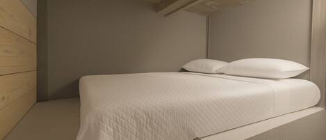 Un dormitorio minimalista con una cama, una pared de madera y un techo de hormigón.