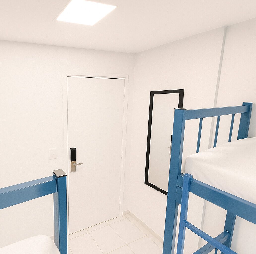 A room with a white door, a bed with a blue frame, and a mirror on the wall.