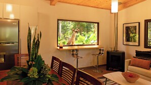A cozy living room with a large window, a fireplace, a dining area, and a kitchen with a refrigerator. - Hotel Boutique Y Restaurante Panisté (San Cristobal Verapaz)