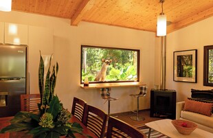 Una sala de estar acogedora con un ventanal grande, una chimenea, un comedor y una cocina con refrigerador.
