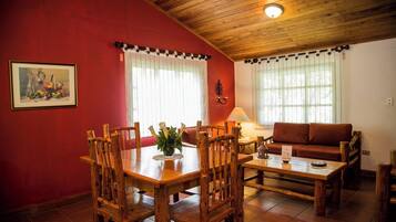 Un comedor con muebles de madera, pared roja y techo con vigas de madera.