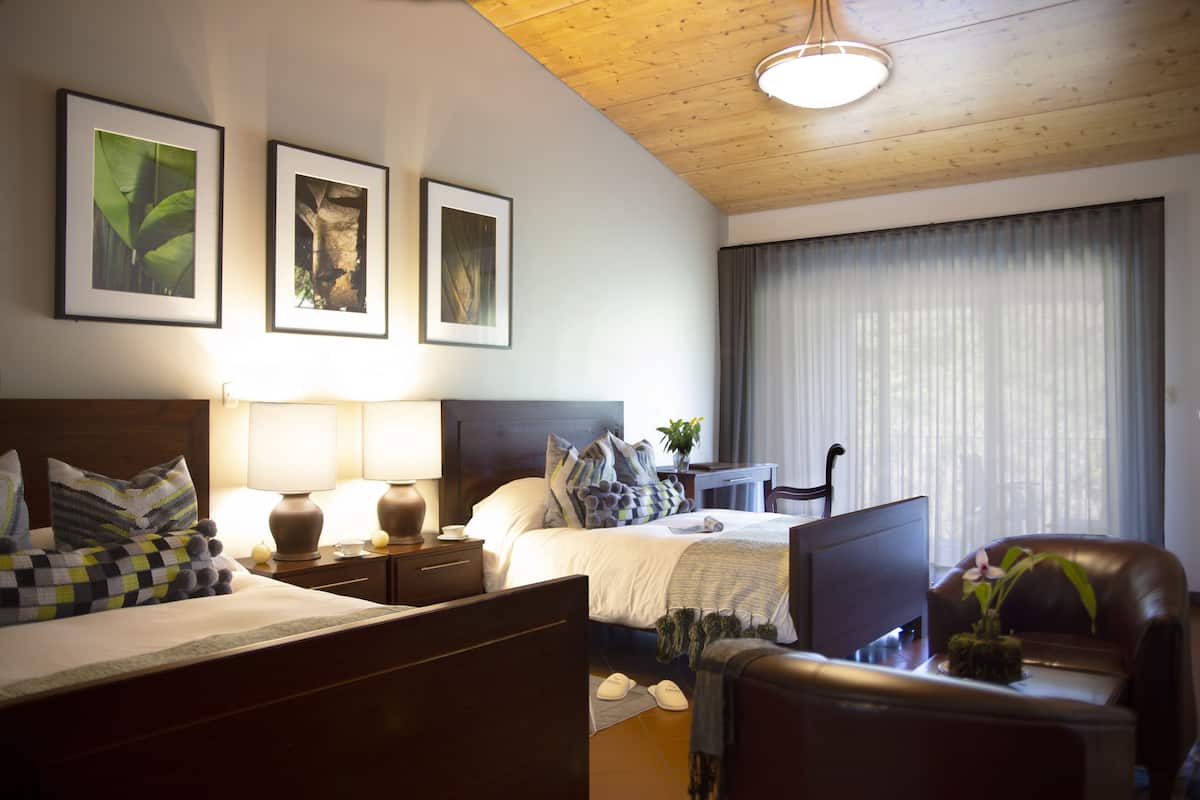 Hotellihuone, jossa on sänky, työpöytä, tuoli, lamppu ja seinällä kehystettyjä kuvia.
