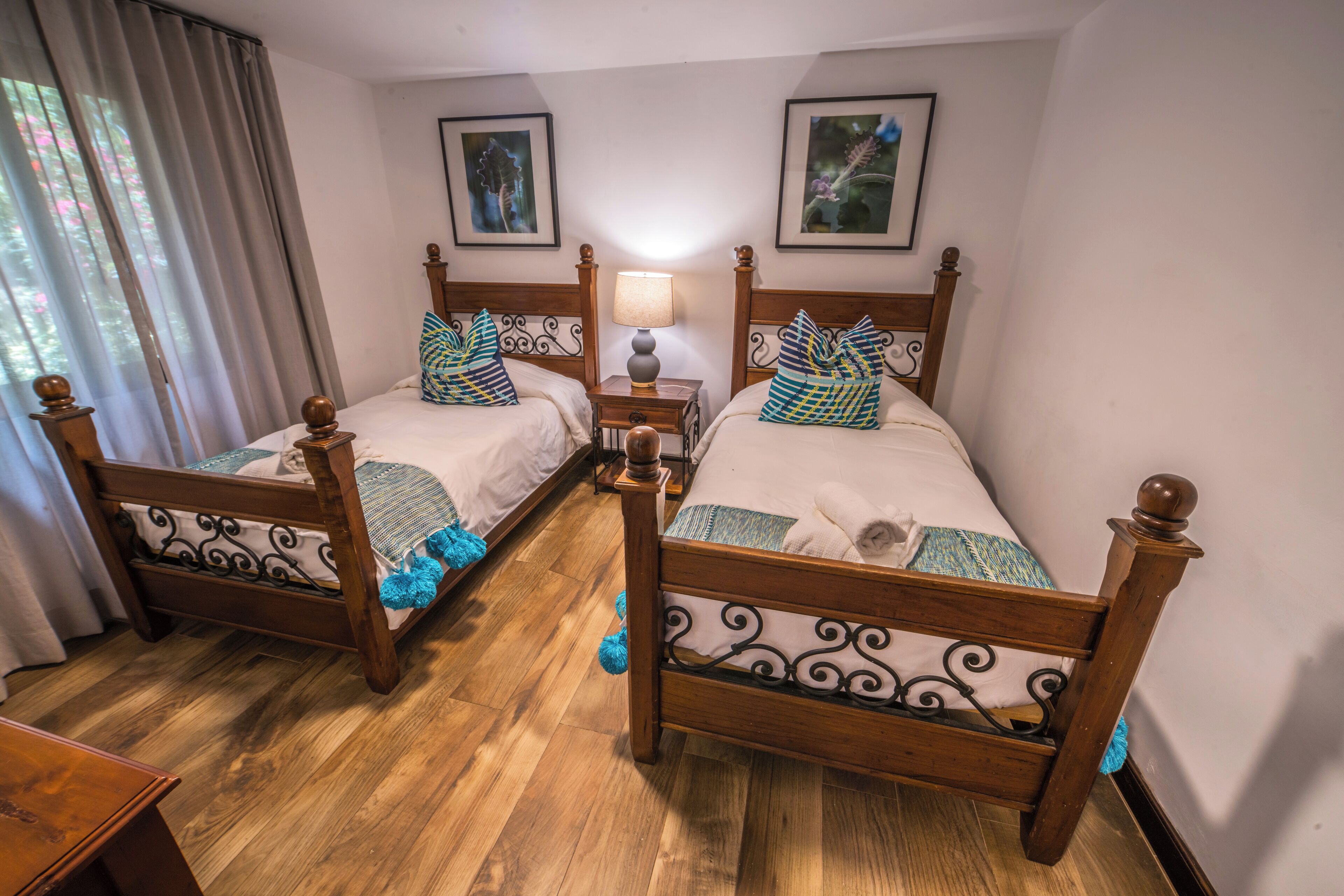 A room with two wooden beds, each with a headboard, a bedside table, and a lamp.