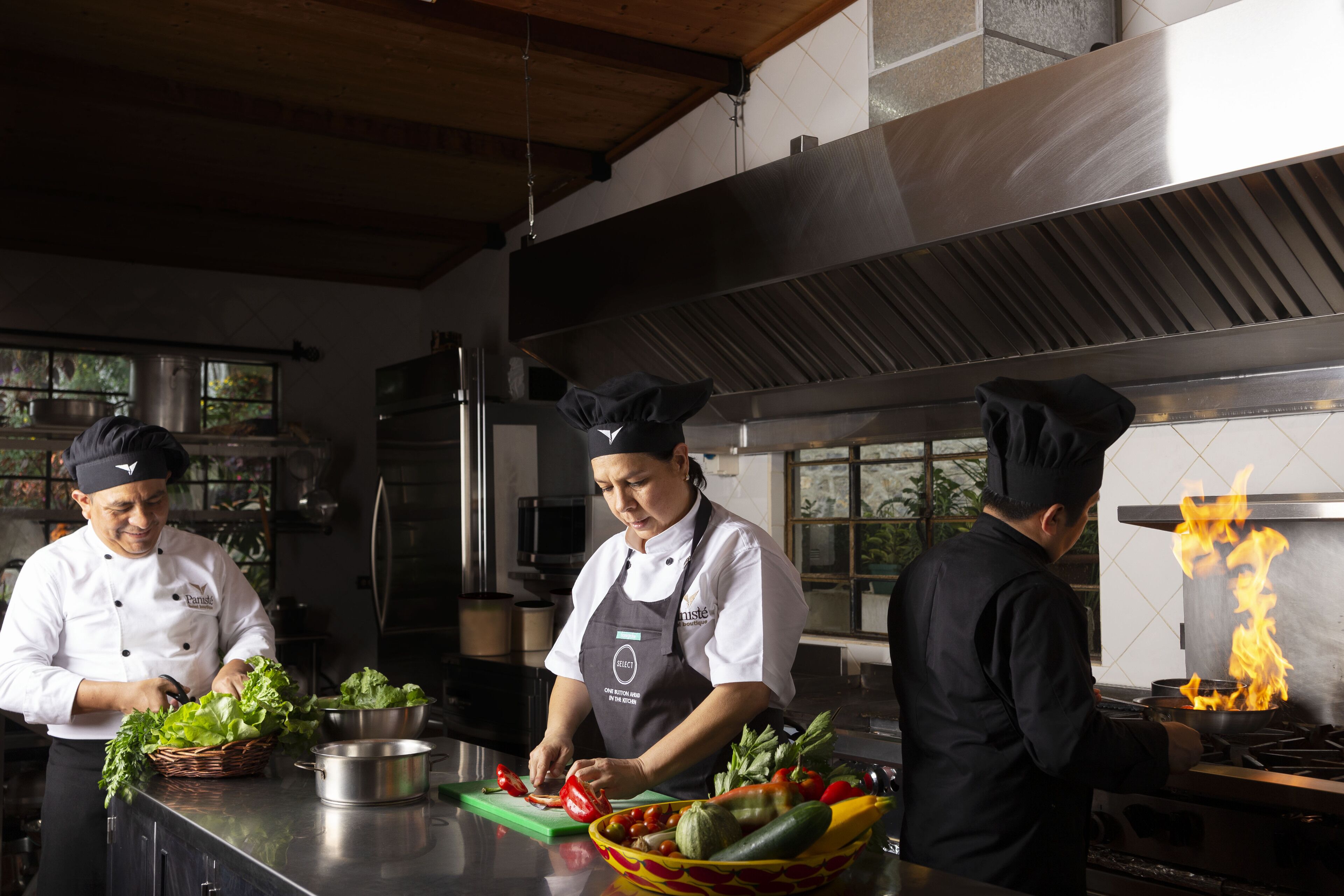 A chef preparing vegetables in a kitchen with a large stove and a window in the background.