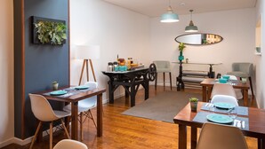 A dining area with wooden tables, chairs, and a central table with a decorative centerpiece. - Bica FLH Suites (Lisbon)
