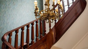 A wooden staircase with a chandelier. - Bica FLH Suites (Lisbon)