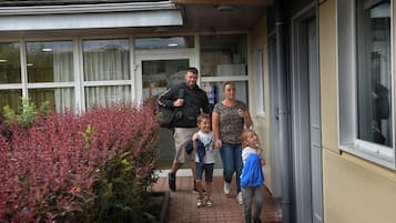 A family walking towards a building with large windows and a brick pathway.