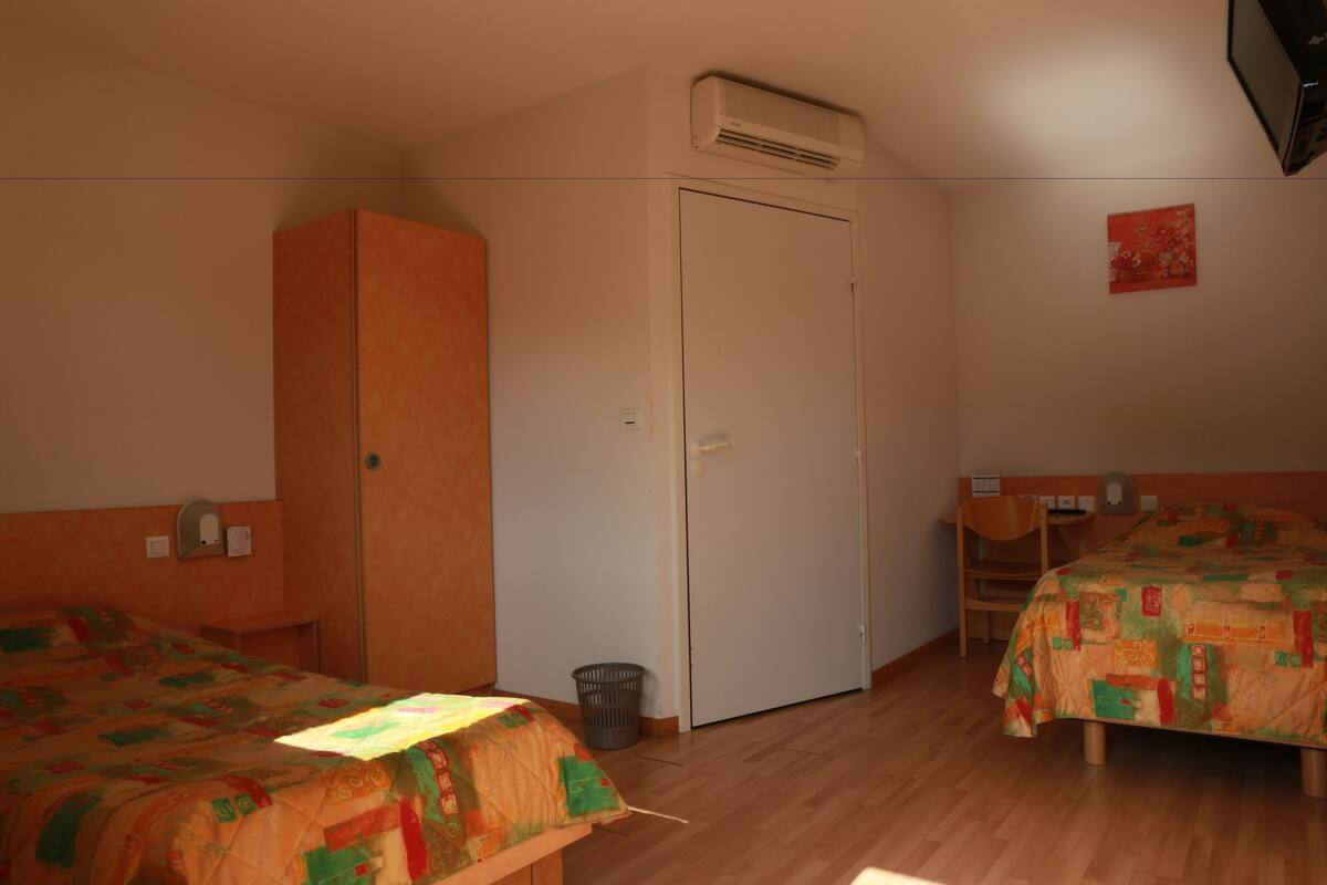Ein Zimmer mit zwei Betten, einem Schrank, einem Schreibtisch und einer Mülltonne.