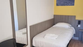 Habitación de hotel con una cama, una silla, un espejo y un cuadro en la pared.