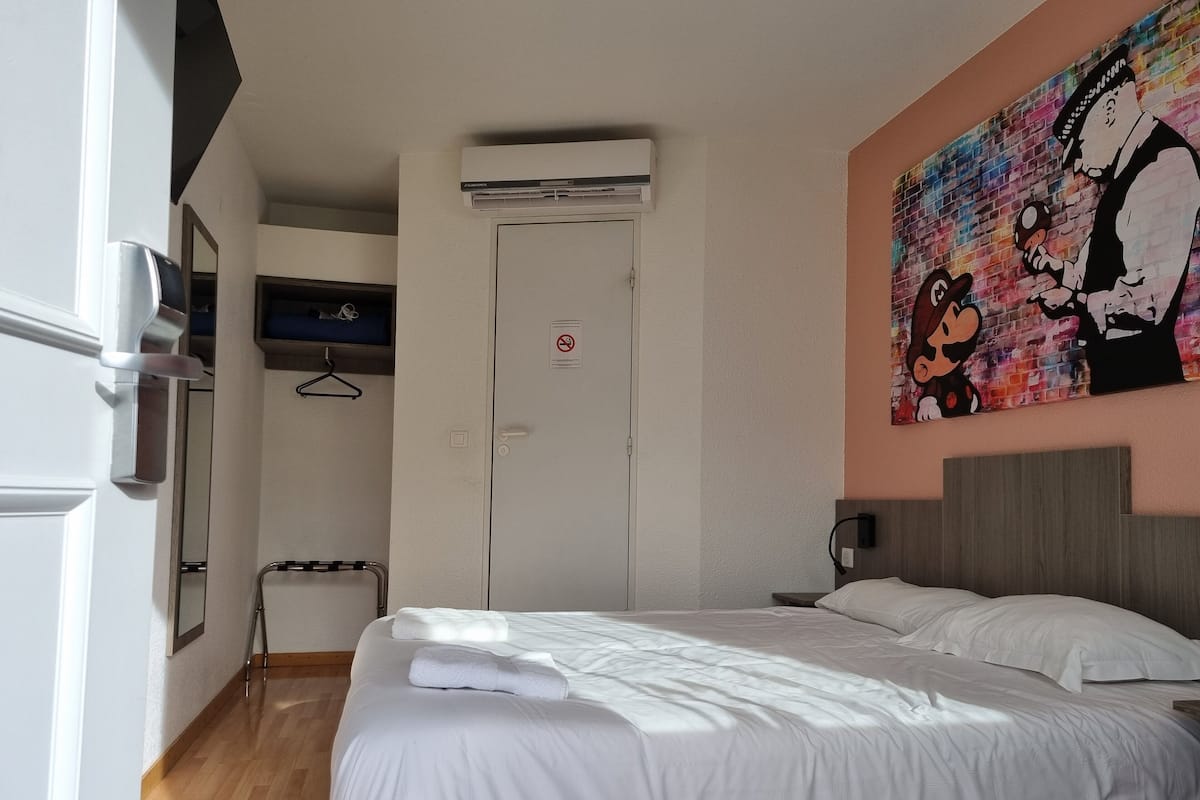 Ein Hotelzimmer mit Bett, Fernseher, Tür und einem Bild an der Wand.