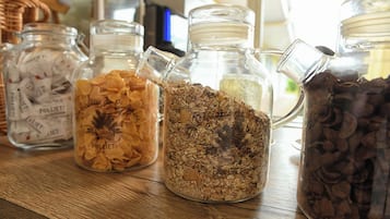 Four glass jars containing different types of cereal on a wooden shelf.