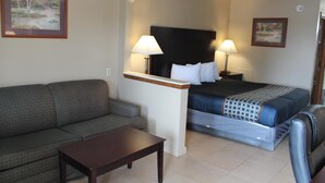 Une chambre d’hôtel avec un lit, un canapé, une petite table et deux lampes.